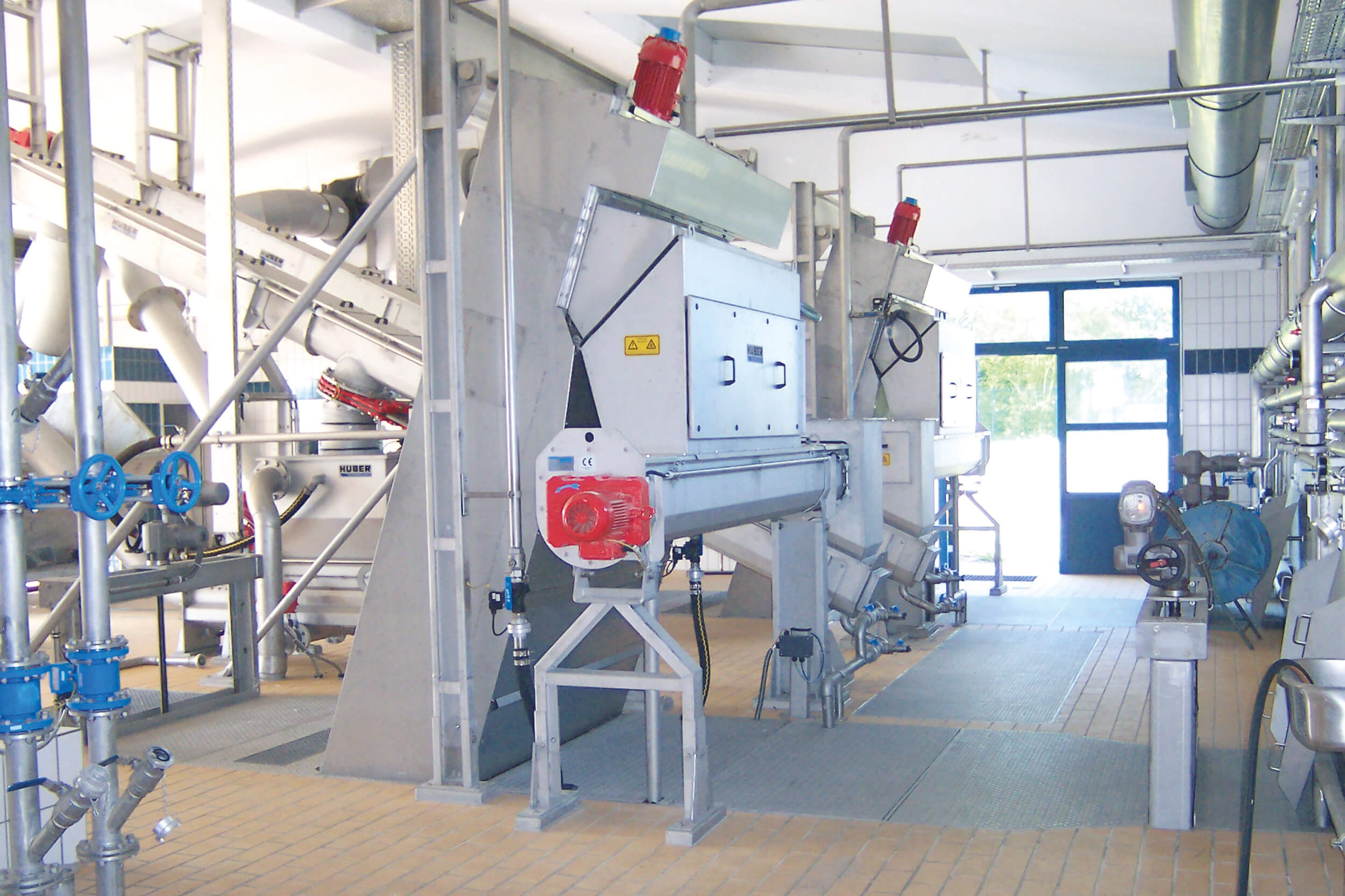 Side view of an enclosed HUBER Fine Screen STEP SCREEN® SSV for odour-free screenings discharge through the transfer chamber with screw conveyor Side view of an enclosed HUBER Fine Screen STEP SCREEN® SSV for odour-free screenings discharge through the transfer chamber with screw conveyor